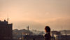 A woman standing in front of a city skyline at sunset